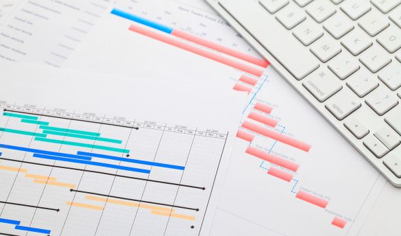 Grafische Darstellung zweier Projektpläne liegt auf Schreibtisch neben weißer Tastatur