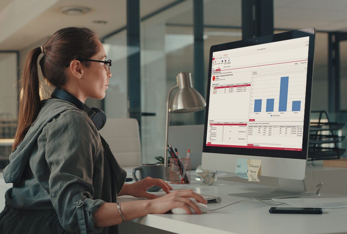 Eine Frau sitzt vor einem Monitor und erstellt eine Lieferantenbewertung