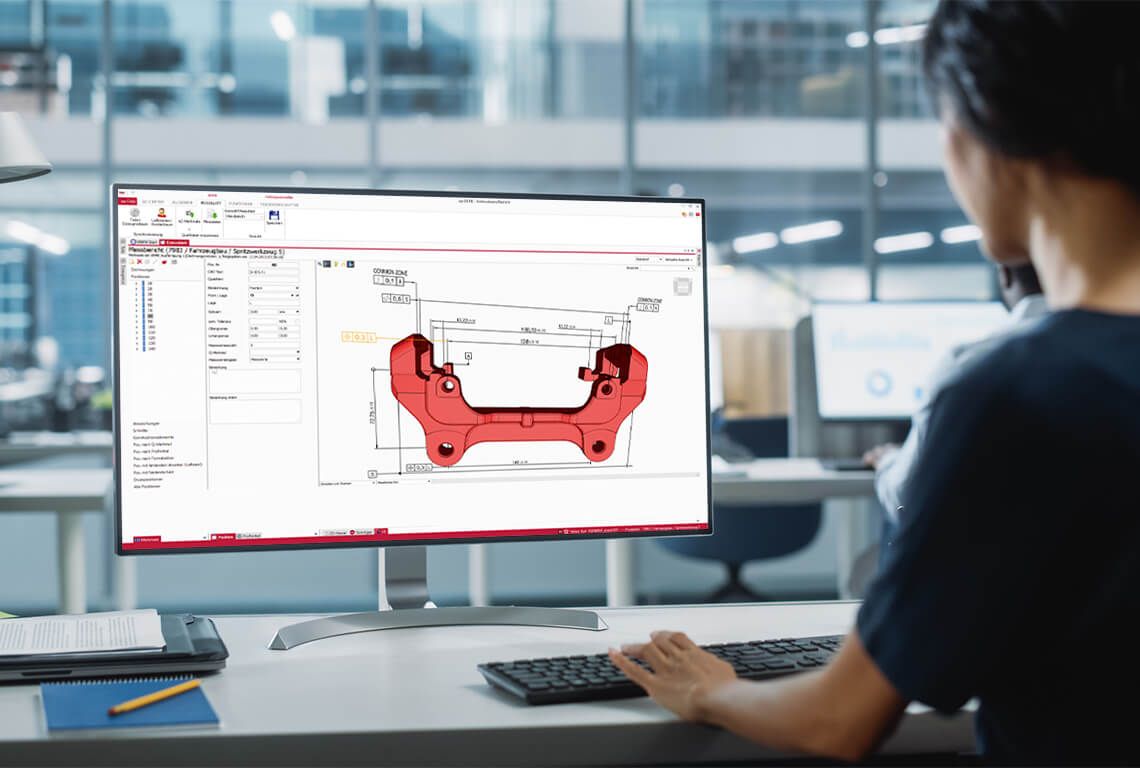 Eine Frau sitzt vor einem Monitor und erstellt einen Erstmusterprüfbericht