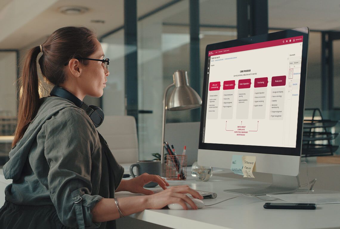 Eine Frau sitzt vor einem Monitor und bearbeitet ein Prozesslandkarte