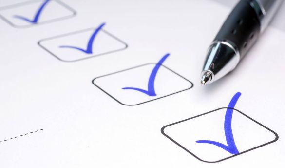 Kugelschreiber liegt auf Papier neben abgehakter Checkliste