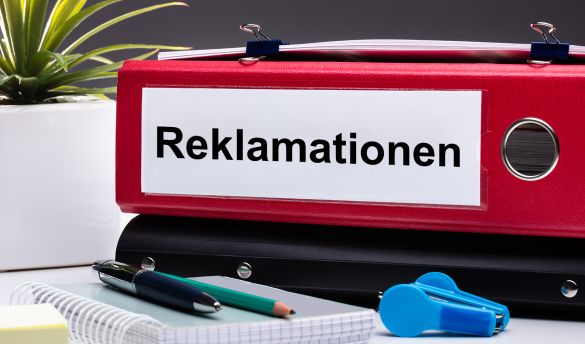 Ordner mit Aufschrift Reklamationen und Bürobedarf auf Schreibtisch