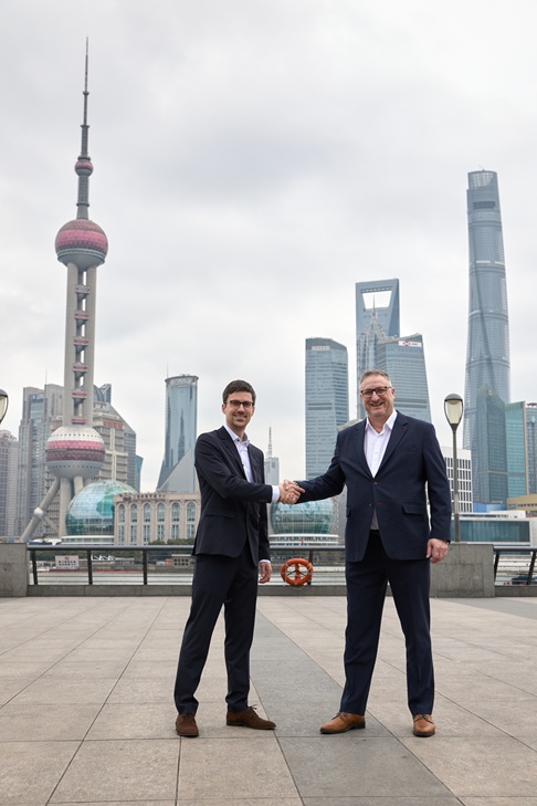 zwei Männer schütteln die Hände. Im Hintergund ist der Shanghai Tower zu sehen